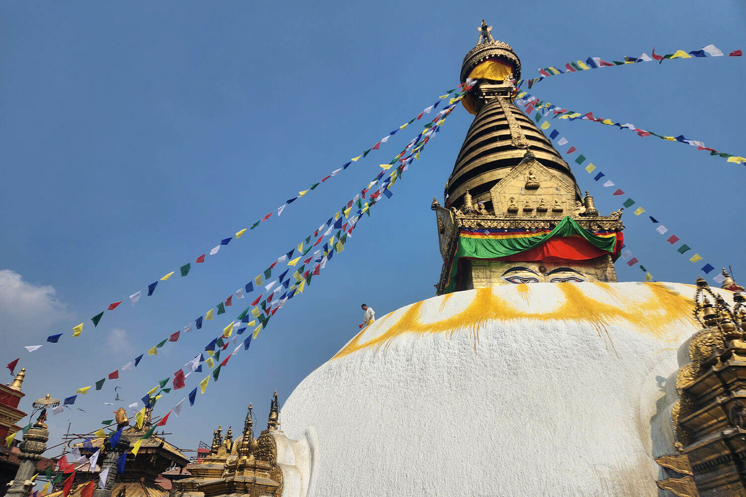 A large white and yellow buddhist temple with many flags.