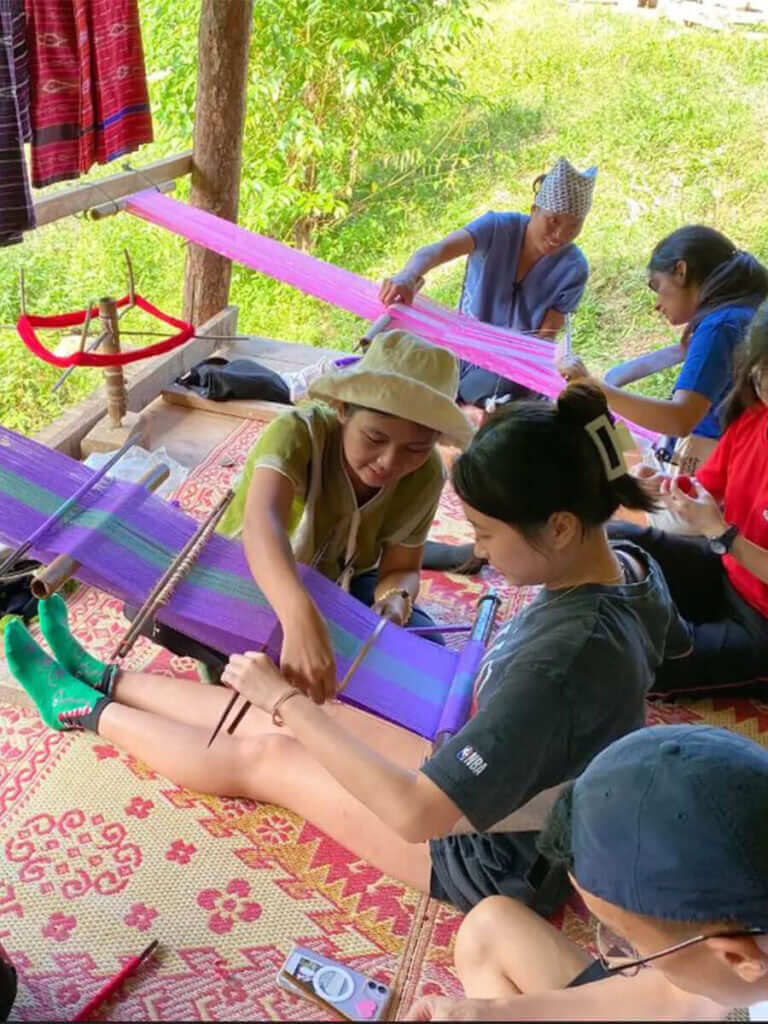 A group of people are working on a weaving project.